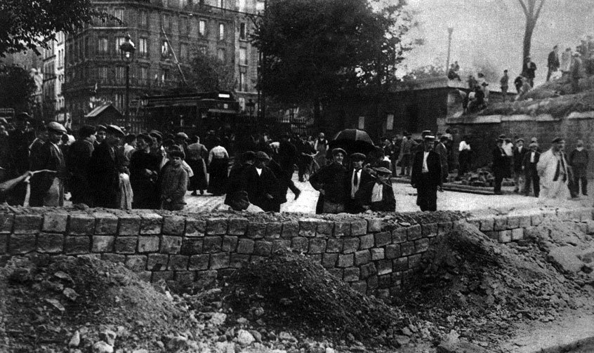 Fortyfikowanie Paryża. Barykada uliczna z kostki brukowej na przedmieściu stolicy Francji. Gdy w sierpniu 1914 roku Niemcy zbliżali się do Paryża, jego mieszkańcy spontaniczne pomagali w działaniach mających służyć obronie swego miasta. Wojna, prowadzona przeciwko całym narodom, mobilizowała całe narody. Z cza-sem same rządy zaczęły traktować obywateli jak ludzi, którzy winni podporządkować się ścisłej dyscyplinie. Fortyfikowanie Paryża. Barykada uliczna z kostki brukowej na przedmieściu stolicy Francji. Gdy w sierpniu 1914 roku Niemcy zbliżali się do Paryża, jego mieszkańcy spontaniczne pomagali w działaniach mających służyć obronie swego miasta. Wojna, prowadzona przeciwko całym narodom, mobilizowała całe narody. Z cza-sem same rządy zaczęły traktować obywateli jak ludzi, którzy winni podporządkować się ścisłej dyscyplinie.